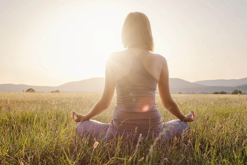 Woman Sitting Cross Legged in a Field Soaking Up the Sun