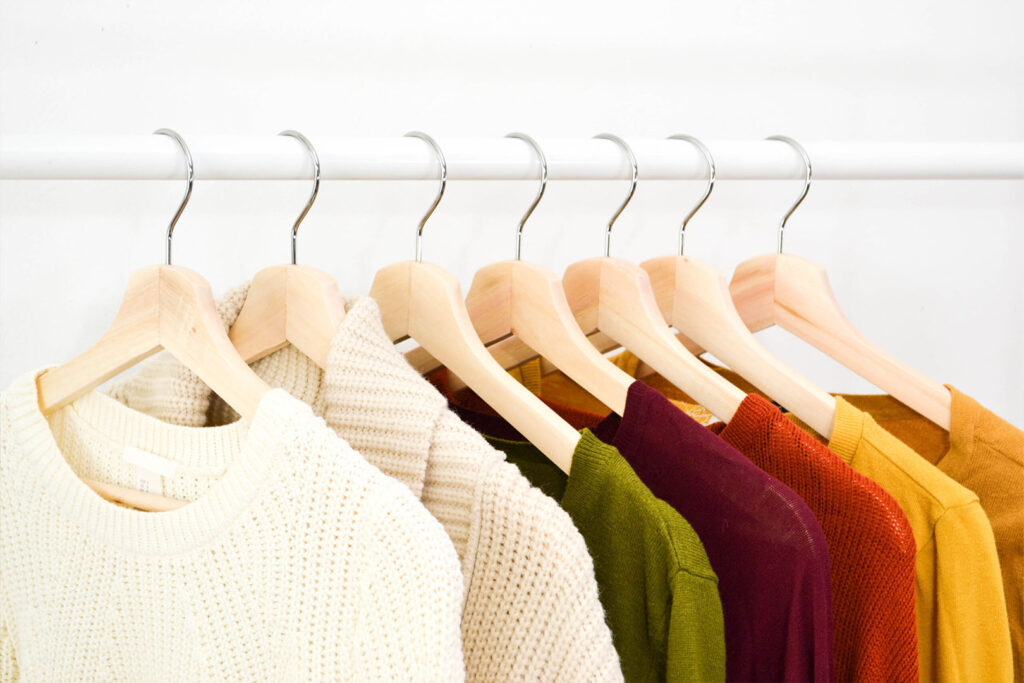 different color sweaters hanging on a rack.