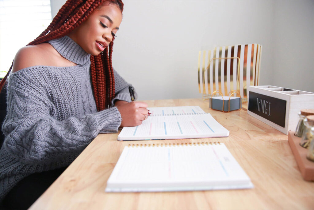 A Woman At a Desk Writing in A Planner