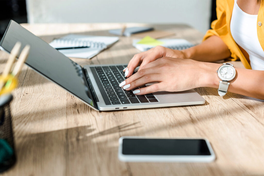 Woman Using Laptop at Wooden Desk Phone on Table