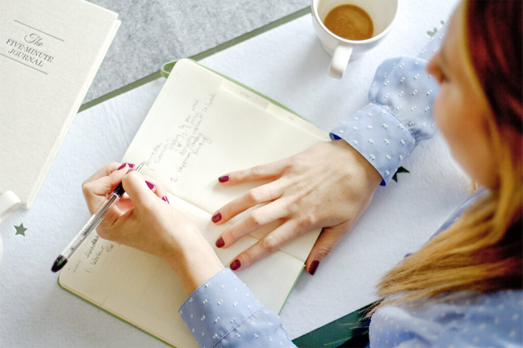 Woman Journaling with Cup of Tea at Desk