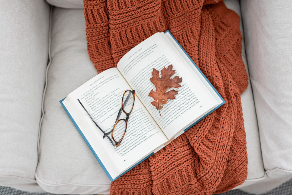 cozy arm chair with blanket book and leaf
