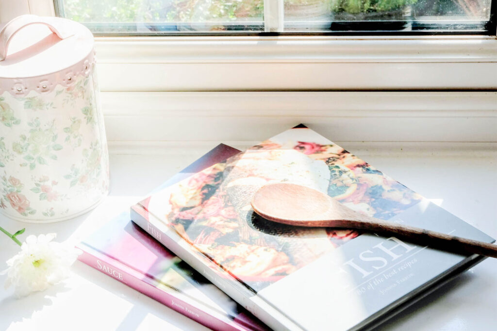 Cookbooks in the window with a flower. Things to do at home.