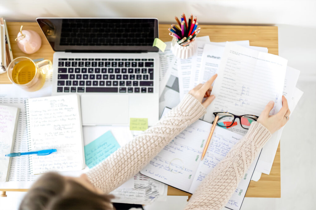 Woman with Laptop and lots of papers.